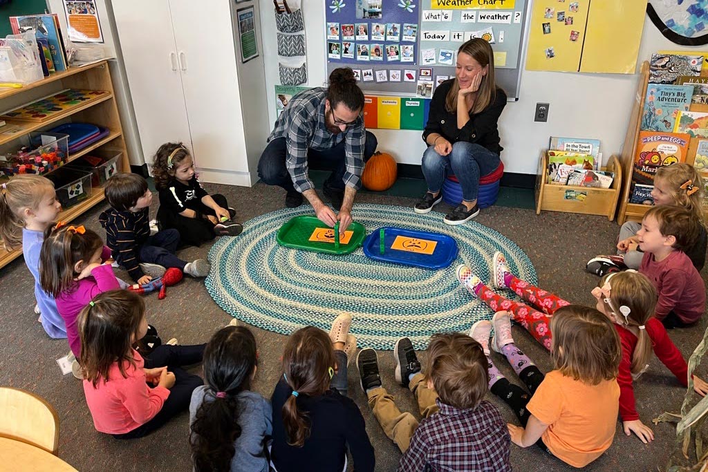 Students with teachers sitting on the ground in a circle