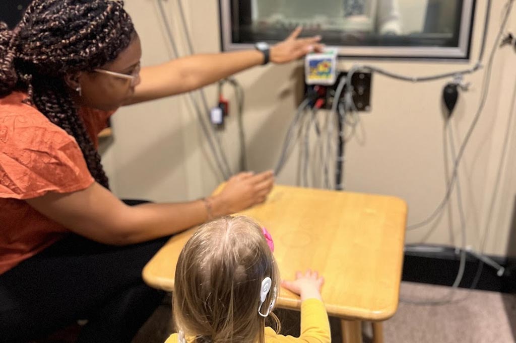 Woman showing a girl with hearing support a screen with another woman