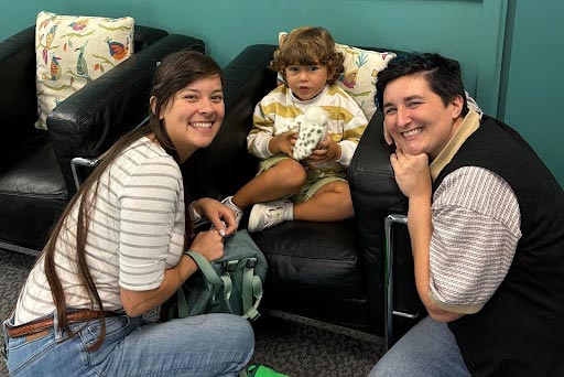Parents smiling in front of kid in chair