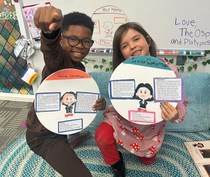 two elementary students with artwork