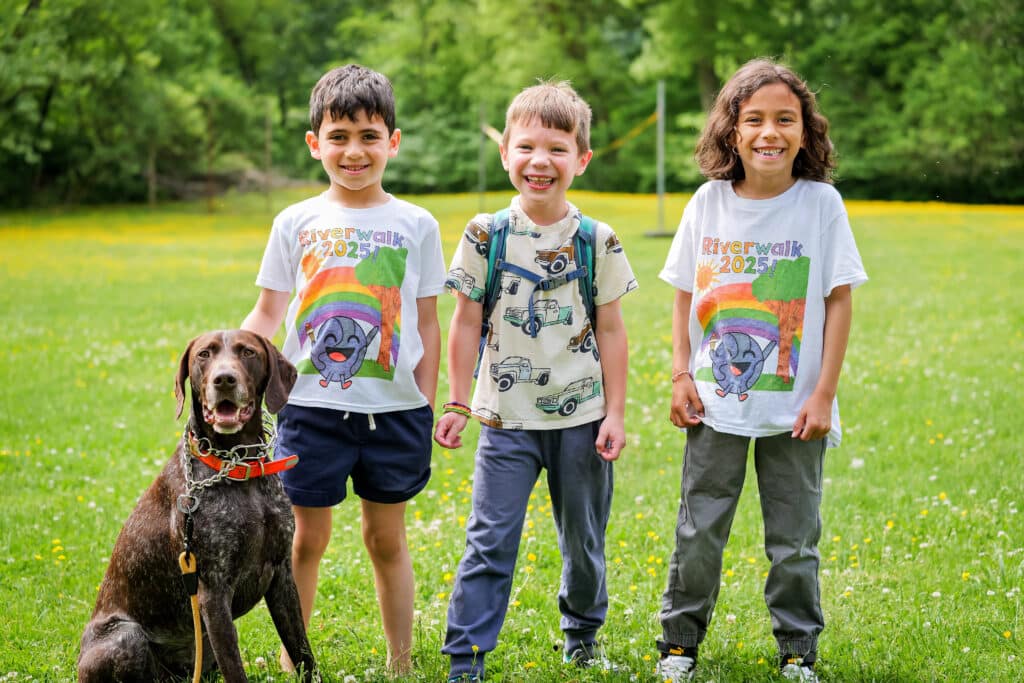 Three children and a dog in a field